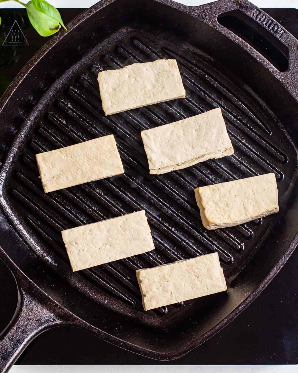 Six small rectangular tofu planks in a grill pan.