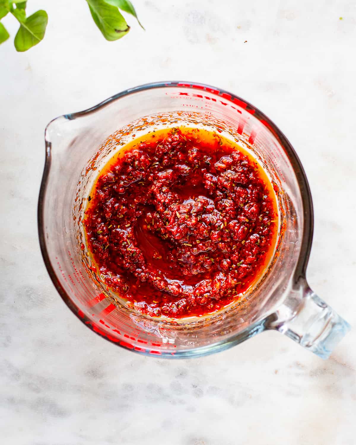Oily harissa sauce in a glass pitcher.