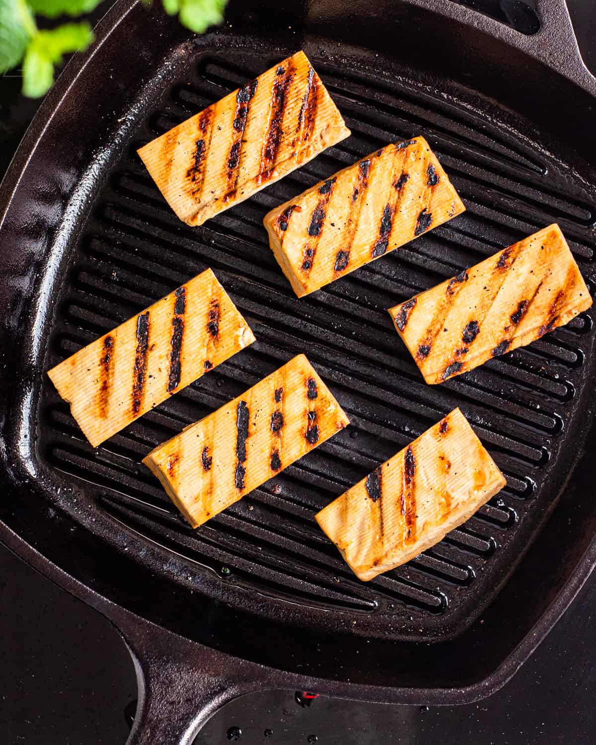 Flipped tofu planks with grill marks in a black cast-iron grill pan.