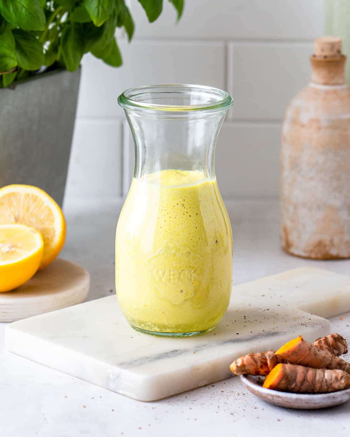 Bright yellow turmeric salad dressing in a glass jar.