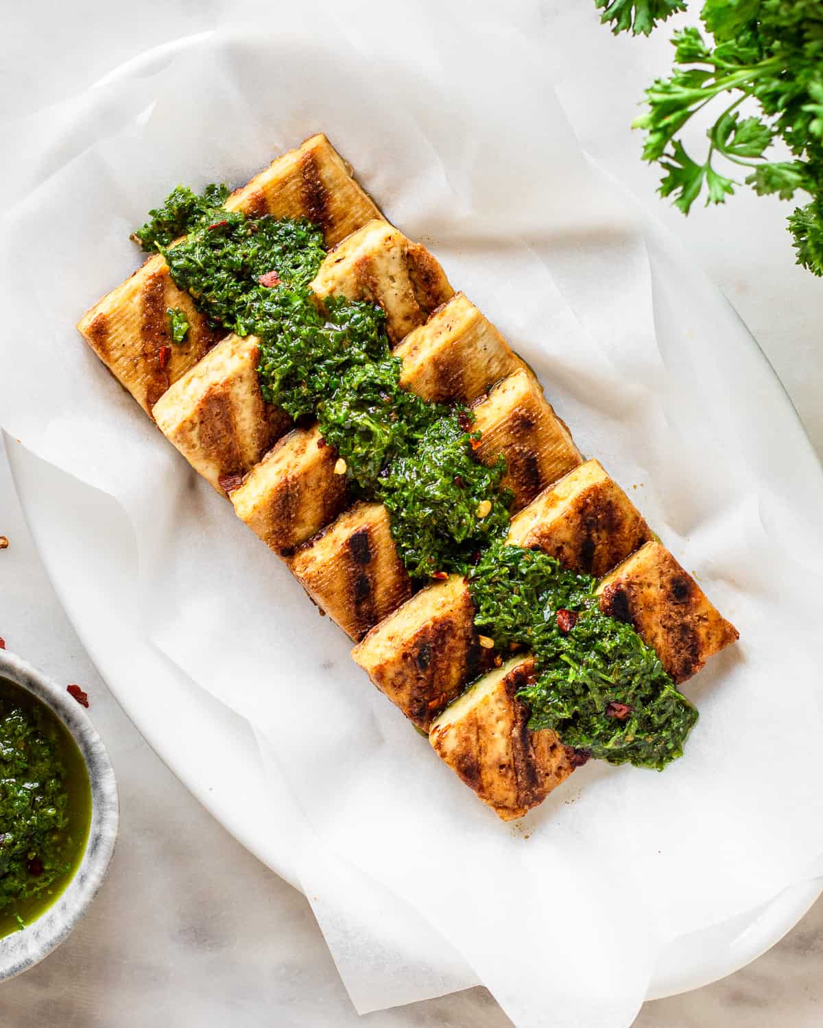 Six pieces of tofu with grill marks and chimichurri on top.