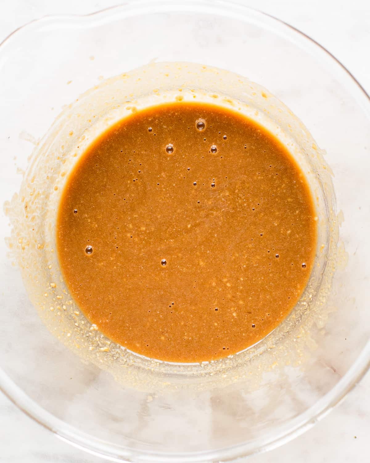 Orange tahini lime dressing in a large glass salad bowl.