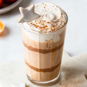 Light brown smoothie garnished with yogurt, a dash of cinnamon and a Christmas biscuit.