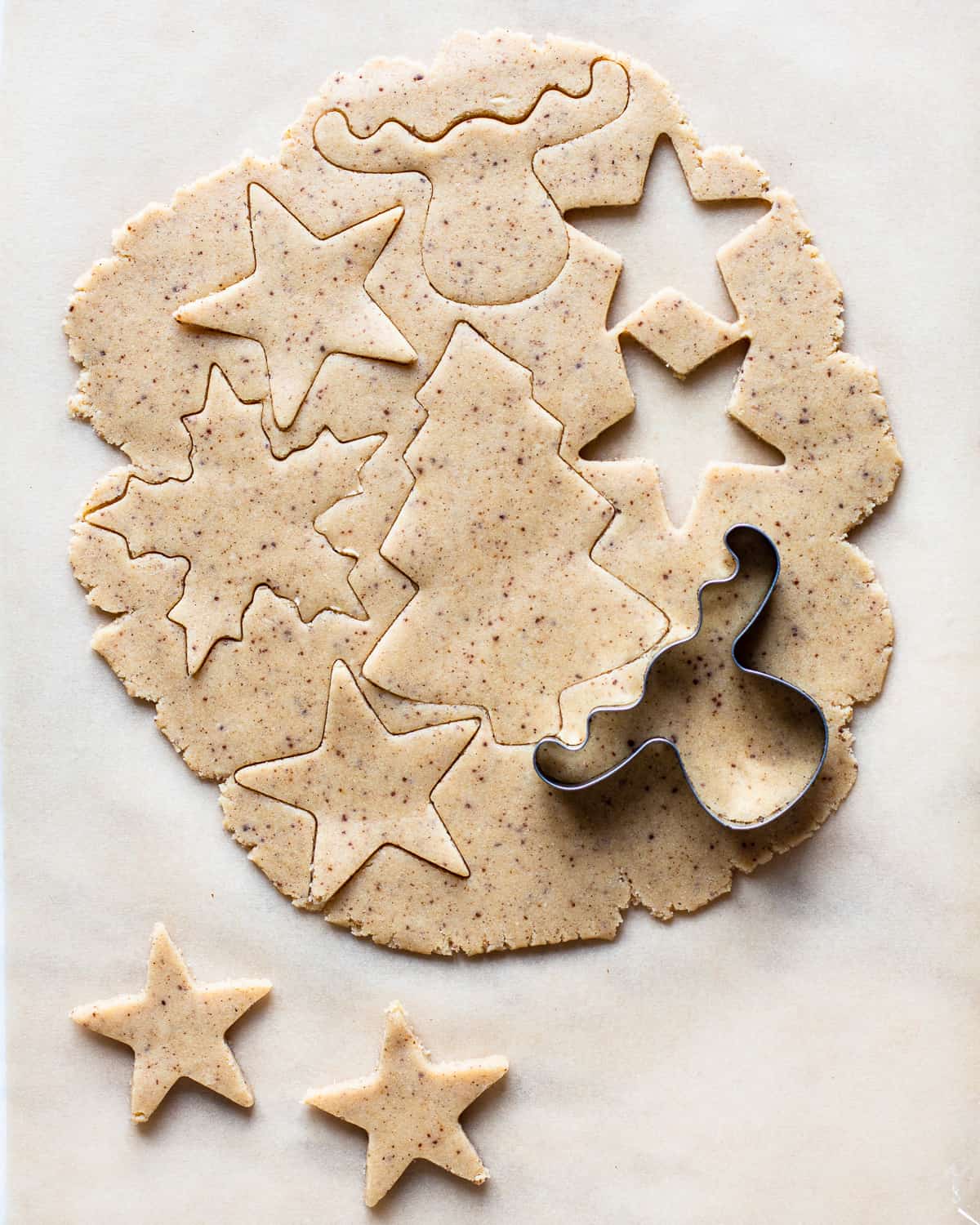 Rolled out sugar cookie dough with christmas cookie cutters.