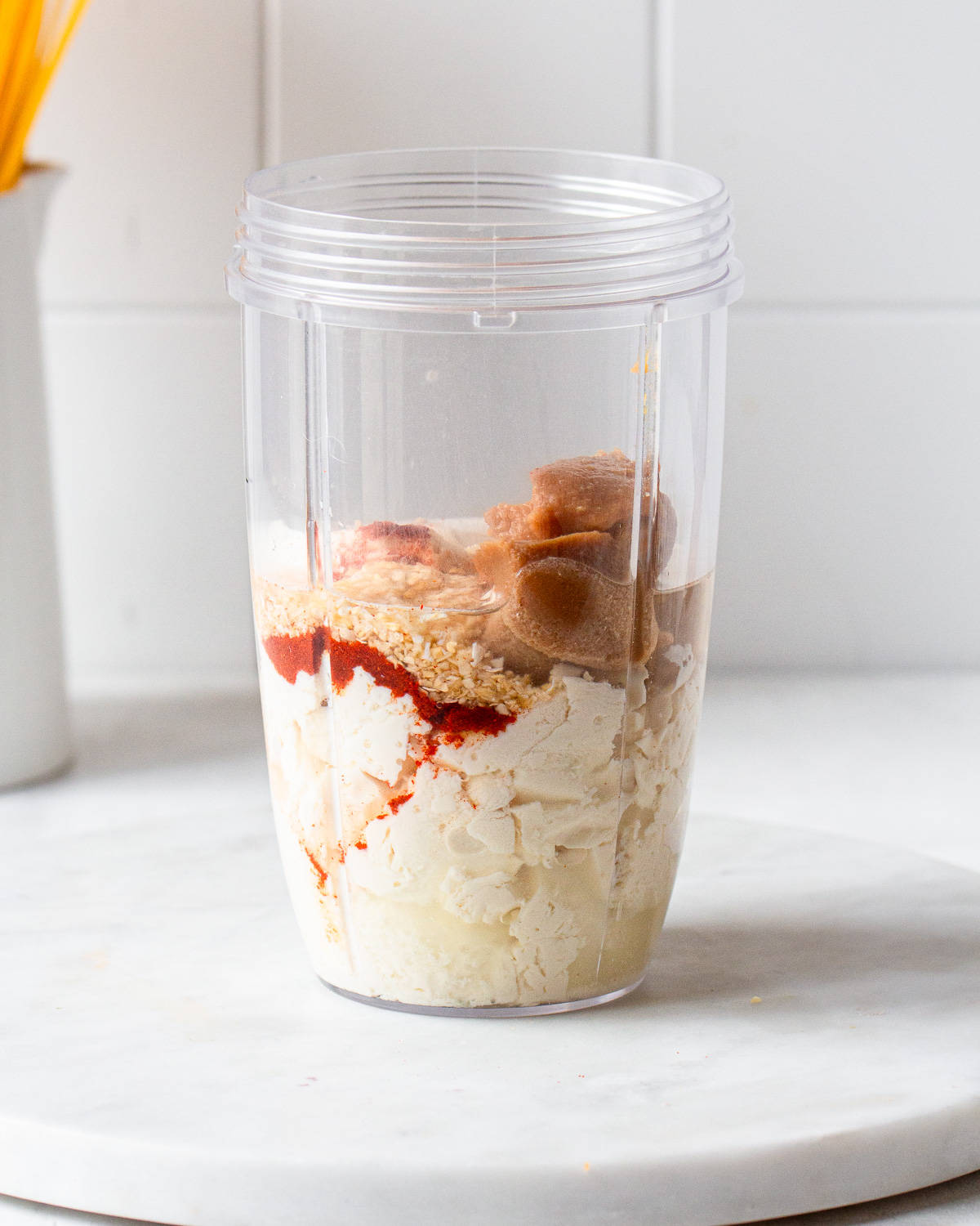 Silken tofu, miso paste, smoked paprika, and onion powder in a blender jug.