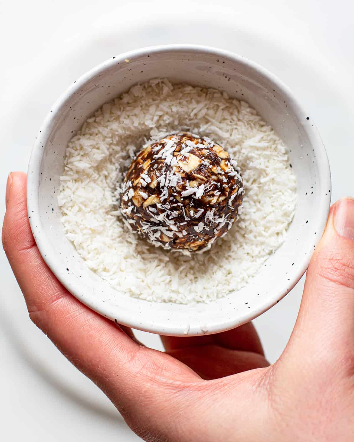 Brown oatmeal energy bowl in a small ball filled with shredded coconut.