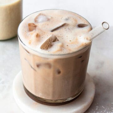 Iced salted caramel latte in a glass with lots of ice cubes and a glass straw.