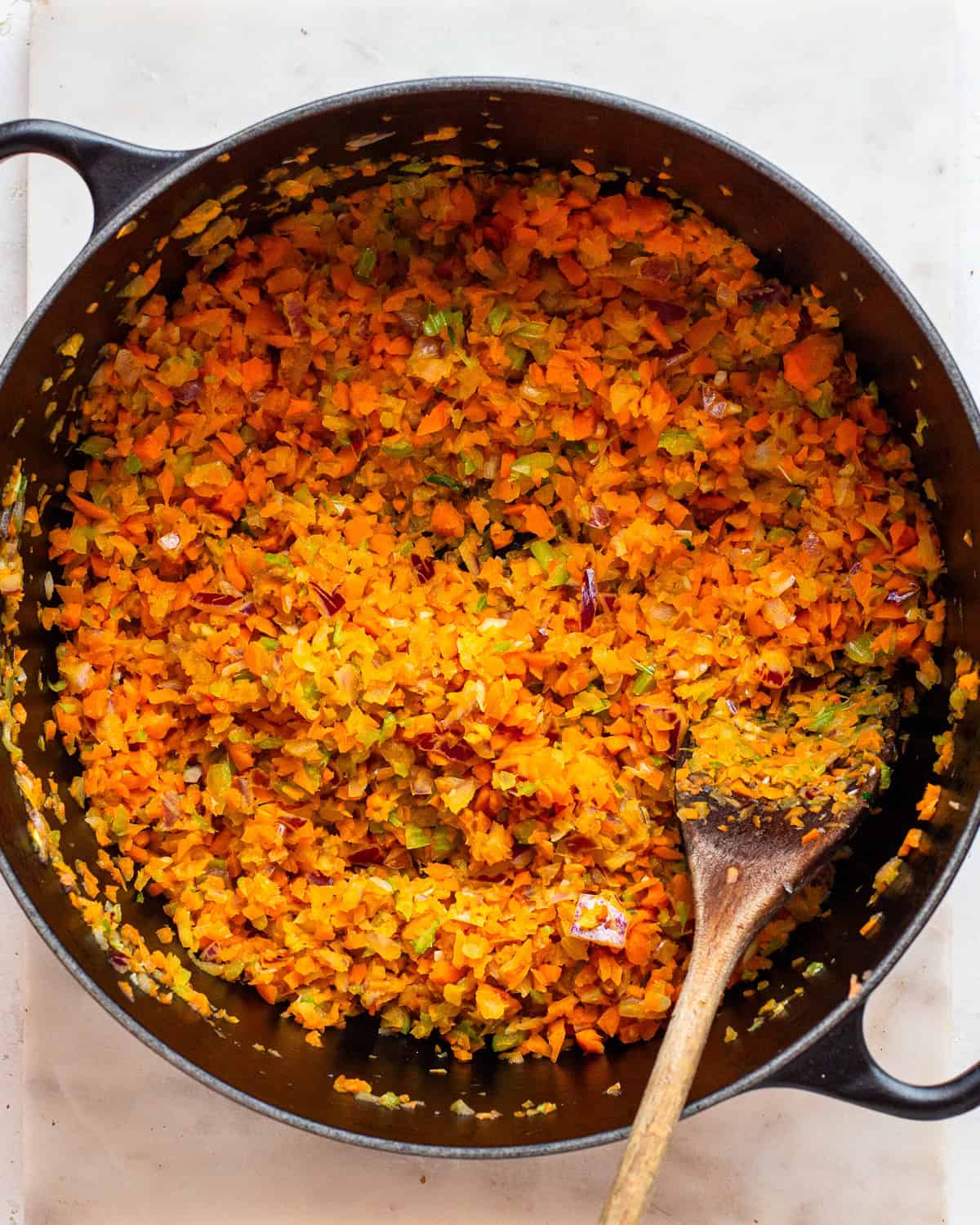 Finely chopped carrots, onion, and celery in a black Dutch-oven.