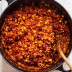 Finished vegan chili with soy crumbles, kidney beans, and corn in a black cast-iron pot.