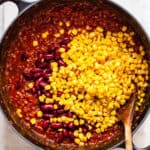 Purple kidney beans and yellow corn in a large black pot with vegan chili.