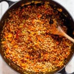 Fine soy crumbles and spices in a black pot with sautéed veggies.